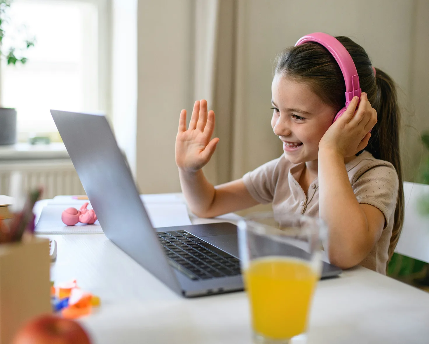 Young learner waving during an online English lesson